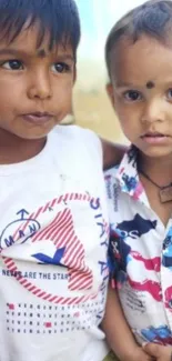 Two adorable children in colorful shirts smiling outdoors.