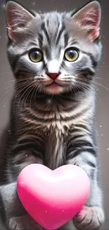 Gray tabby kitten holding a pink heart balloon.