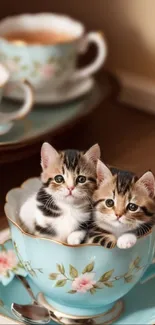 Two adorable kittens sitting in a blue floral teacup.