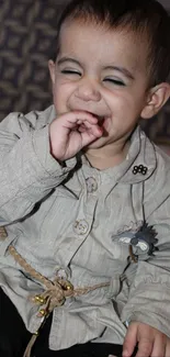 Adorable baby laughing with closed eyes, wearing beige outfit.