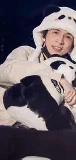 Person in panda costume hugging a plush panda.