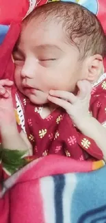 Adorable sleeping baby wrapped in a red blanket.