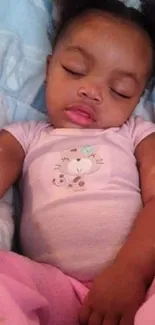 Adorable baby asleep in pink pajamas on pastel bedding.