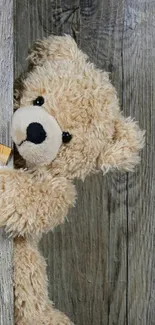 Cuddly teddy bear peeking from rustic wooden background.