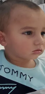 Adorable toddler with a serene expression wearing a light blue shirt.