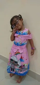 Adorable toddler in pink dress with colorful cartoon design.