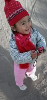 Cute child in winter clothes with red hat smiling joyfully.