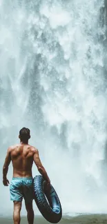 Man standing by waterfall holding inflatable tube.