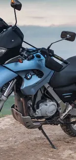 Sky-blue motorcycle on a hilltop overlooking a city at dusk.