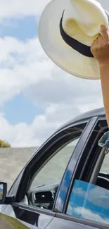 Hand with hat out of car window on sunny day.