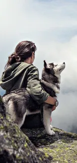 Person and Husky on a foggy mountain peak, capturing a serene adventure moment.