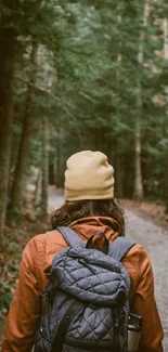 Person with backpack walking down a forest path.