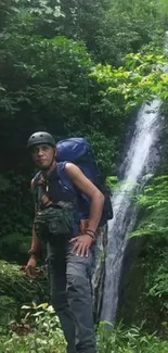 Hiker standing beside a scenic waterfall amidst lush greenery.