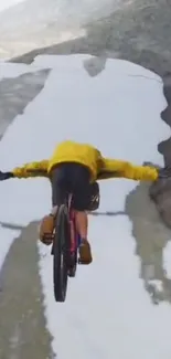 Cyclist in yellow jacket descending snowy mountain path.