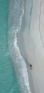 Aerial view of a turquoise beach with gentle waves and soft sand.