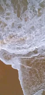 Aerial view of ocean waves and sandy beach creating a natural texture.