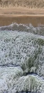 Aerial view of ocean waves crashing on a sandy beach.