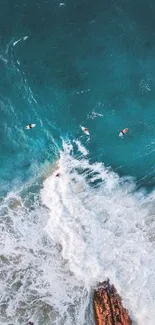 Aerial view of surfers navigating ocean waves near rocky coast.