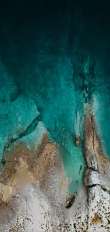 Aerial view of ocean meeting rocky shore with vibrant aqua hues.