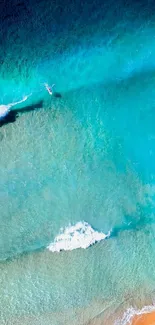 Aerial view of turquoise ocean with waves and sandy beach.