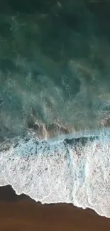 Aerial view of ocean waves crashing on a sandy beach shore, captured in serene detail.