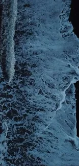 Aerial view of ocean waves crashing against the shore at night.