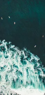 Aerial ocean view with crashing waves and surfers.