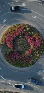 Aerial view of a roundabout with cars and pink flowers.