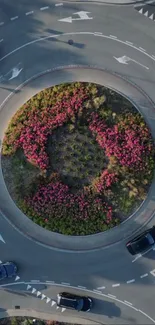 Aerial view of a roundabout with colorful flowers and cars.