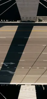 Aerial view of bridge casting large shadow over road.