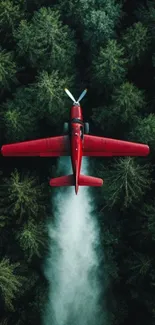 Red aircraft flying over dense green forest.