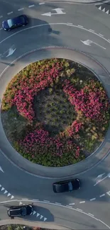 Aerial view of roundabout with pink flowers and cars.