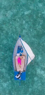 Aerial view of a sailboat on turquoise water from above.