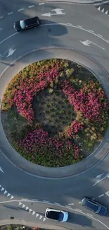 Aerial view of a roundabout with cars and colorful flowers.