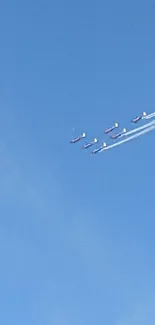 Aerobatic planes flying in formation across a bright blue sky.