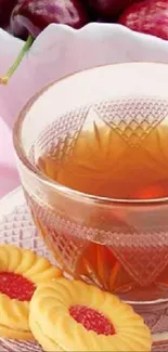 Crystal cup of tea with cookies and cherries on a light pink background.