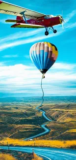 Plane towing a hot air balloon over a winding road under a blue sky.