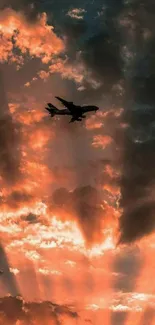 Silhouetted airplane against a fiery sunset sky with dramatic clouds.