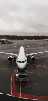 Commercial airplane on runway at airport terminal on a cloudy day.