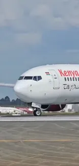 Kenya Airways airplane on runway preparing for takeoff.