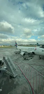 LATAM airplane parked on airport tarmac with cloudy sky.