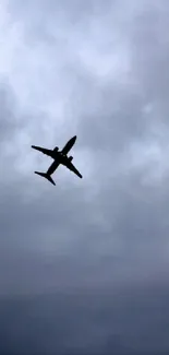 Silhouette of airplane against cloudy sky.