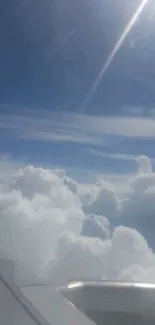 Airplane window view with clouds and blue sky.