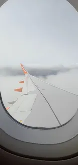 Airplane wing view through window over clouds.