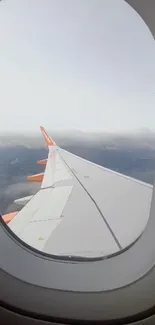 Airplane wing view from a window showcasing clouds and sky.