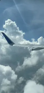 Airplane wing above fluffy clouds and blue sky.