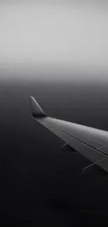 Airplane wing piercing through grey fog.