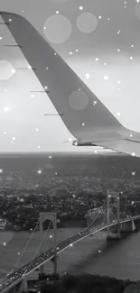 Monochrome image of an airplane wing over a city and river bridge.