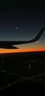 Silhouette of an airplane wing at sunset with a crescent moon in the sky.