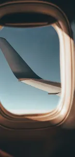 Airplane wing seen through window with clear blue sky in background.